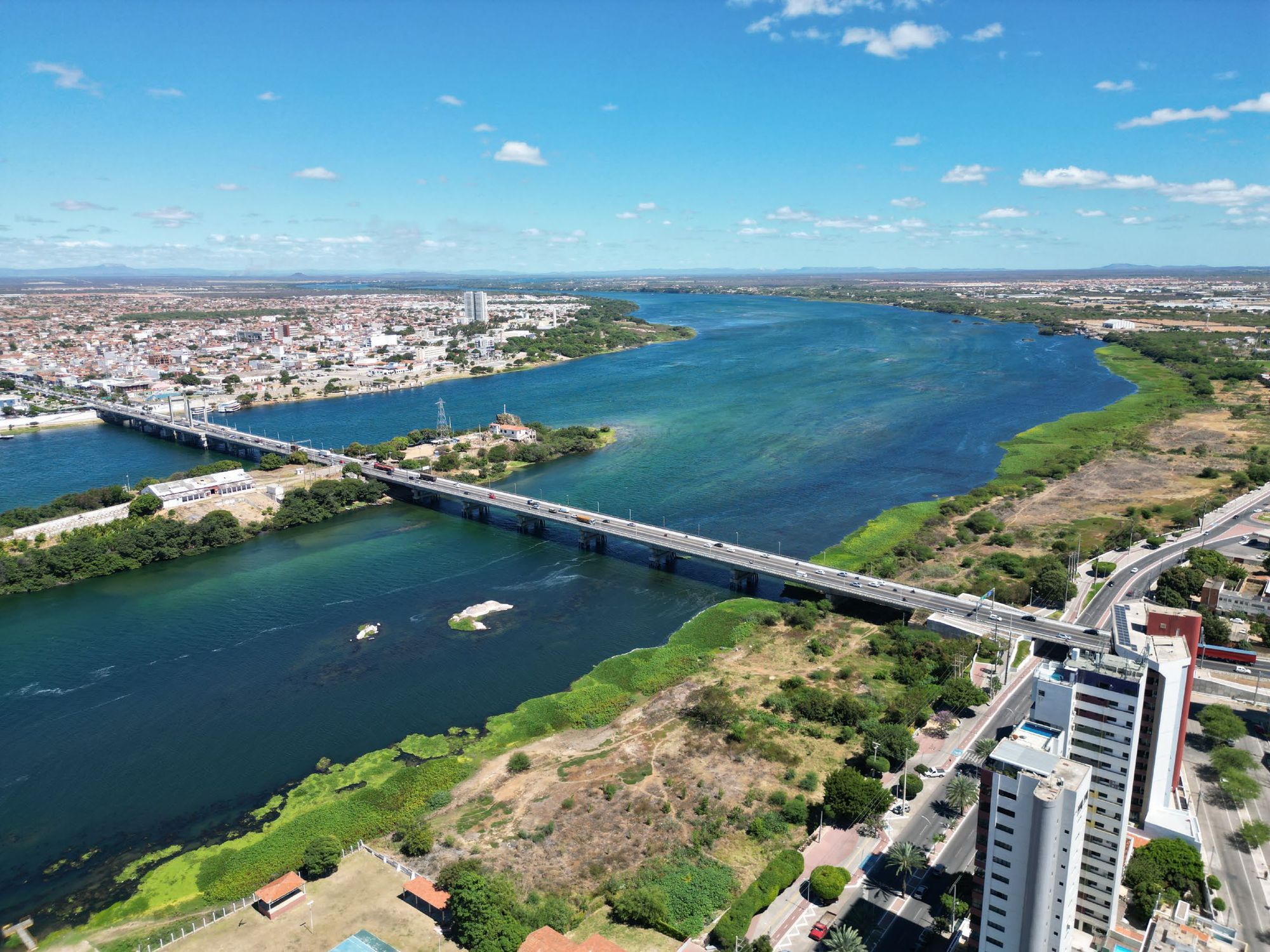 Vista aérea do Rio São Francisco e da Ponte Presidente Dutra; à direita, a orla de Petrolina com seus edifícios.