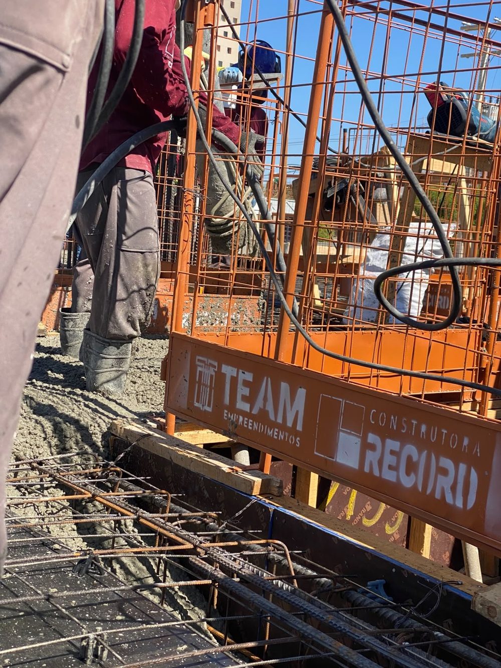 O equipamento de bombeamento no canteiro, com as marcas da TEAM e da Construtora Record.