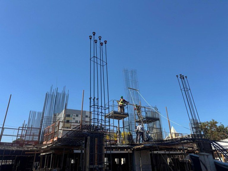 As armaduras dos pilares do pavimento de lazer montadas, recortadas contra o céu.