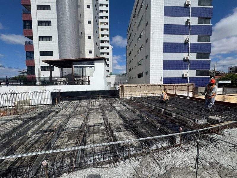 A laje da segunda etapa do pilotis em montagem, com os edifícios da orla ao fundo.