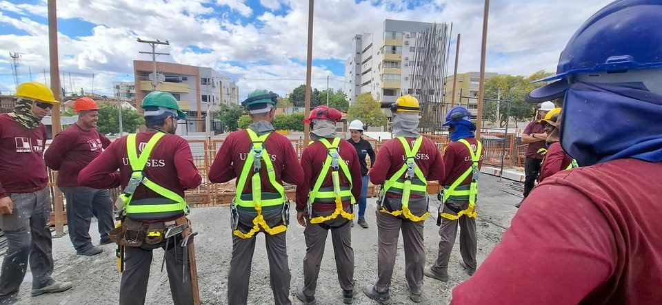Equipe perfilada com os cintos de segurança, no treinamento de trabalho em altura.